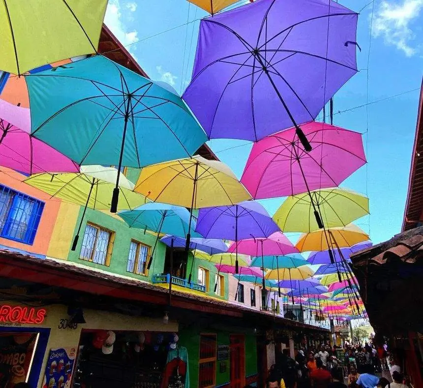 Calle de Guatapé decorada con sombrillas de colores sobre casas de fachadas pintadas