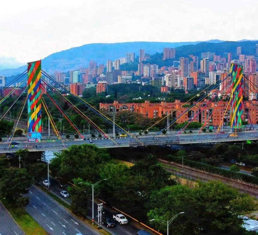 Puente atirantado de colores con el skyline de Medellín al fondo