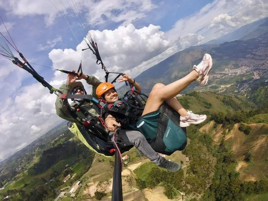 Pareja disfrutando un vuelo en parapente con nubes al fondo