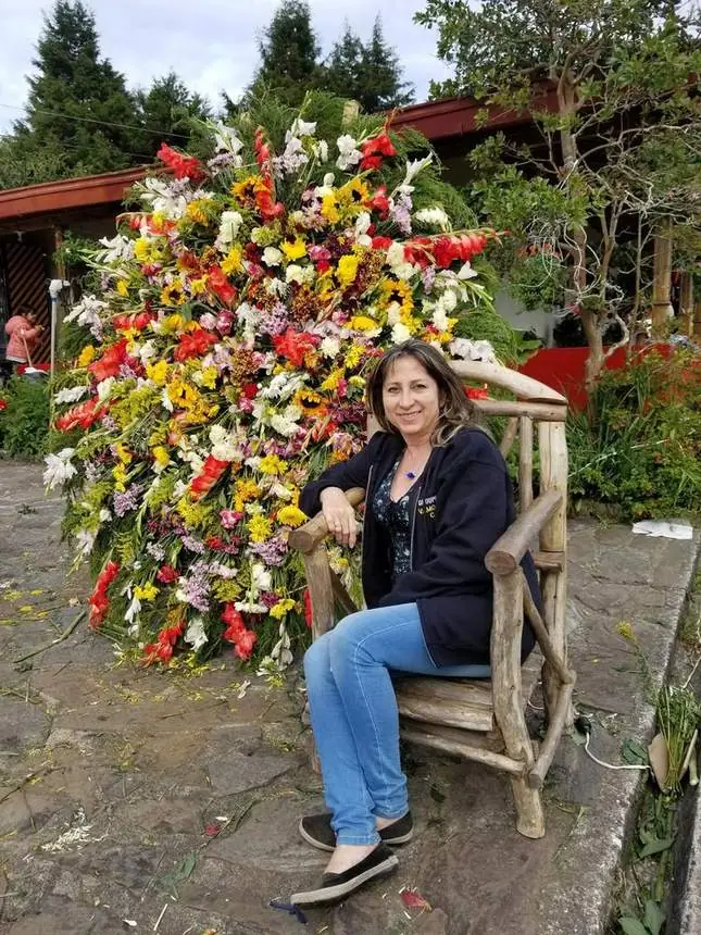Visitante junto a una silleta decorada con flores